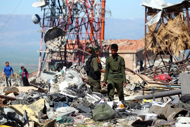 Syrian Kurdish fighters stand on debris of a building destroyed as a result of Turkish airstrikes. Photo: AFP