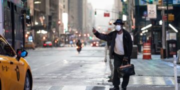 A man wearing a mask tries to catch a taxi at Times Square amid the COVID-19 pandemic on April 30, 2020 in New York City