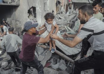 Men pass a young girl to safety over rubble in Jabalia Refugee Camp, Gaza Strip, on May 18, 2025. Search and rescue teams rescue a Palestinian girl from under the rubble after the Israeli army attacked a building at the Jabalia Refugee Camp