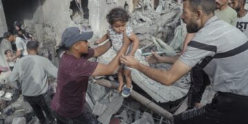 Men pass a young girl to safety over rubble in Jabalia Refugee Camp, Gaza Strip, on May 18, 2025. Search and rescue teams rescue a Palestinian girl from under the rubble after the Israeli army attacked a building at the Jabalia Refugee Camp